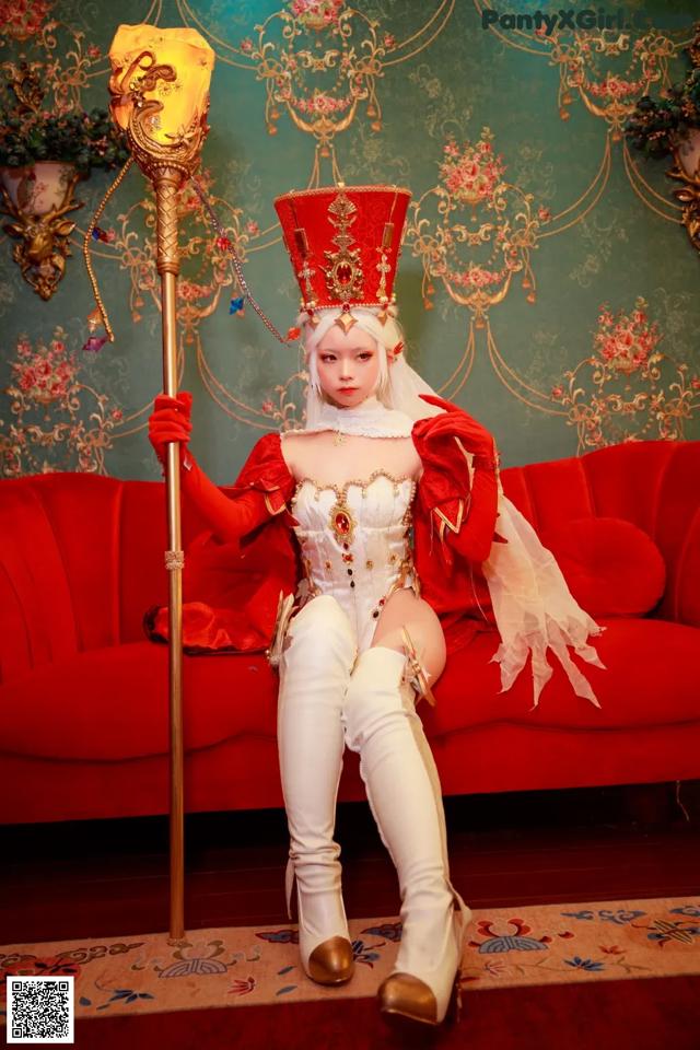 A woman in a red and white outfit sitting on a red couch.