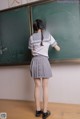 A woman standing in front of a blackboard in a classroom.