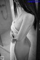 A naked woman standing in a bathroom with a towel around her neck.