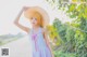 A woman in a blue dress and a straw hat posing for a picture.