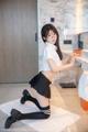 A woman in a school uniform posing in front of a sink.