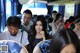 A group of people sitting on a bus looking at their cell phones.