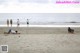 A man laying on the sand on a beach next to the ocean.