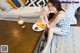 A woman sitting on the floor eating donuts and a drink.