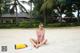 A woman in a pink bathing suit sitting on the beach.