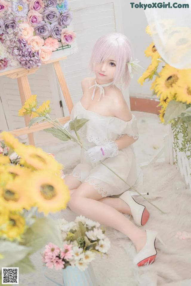 A woman sitting on the floor next to a bunch of flowers.