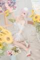 A woman in a white dress sitting on the floor next to a bunch of flowers.