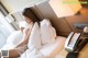 A woman sitting on a bed next to a telephone.