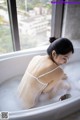 A woman sitting in a bathtub with foam in it.