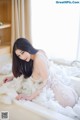 A woman in a white lingerie sitting in a bathtub.