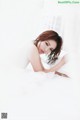 A woman laying on top of a bed covered in white sheets.