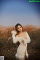 A woman in a white dress standing in a field.