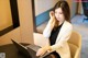 A woman sitting at a table using a laptop computer.