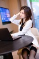 A woman sitting at a table with a laptop computer.