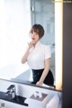 A woman standing in front of a mirror in a bathroom.