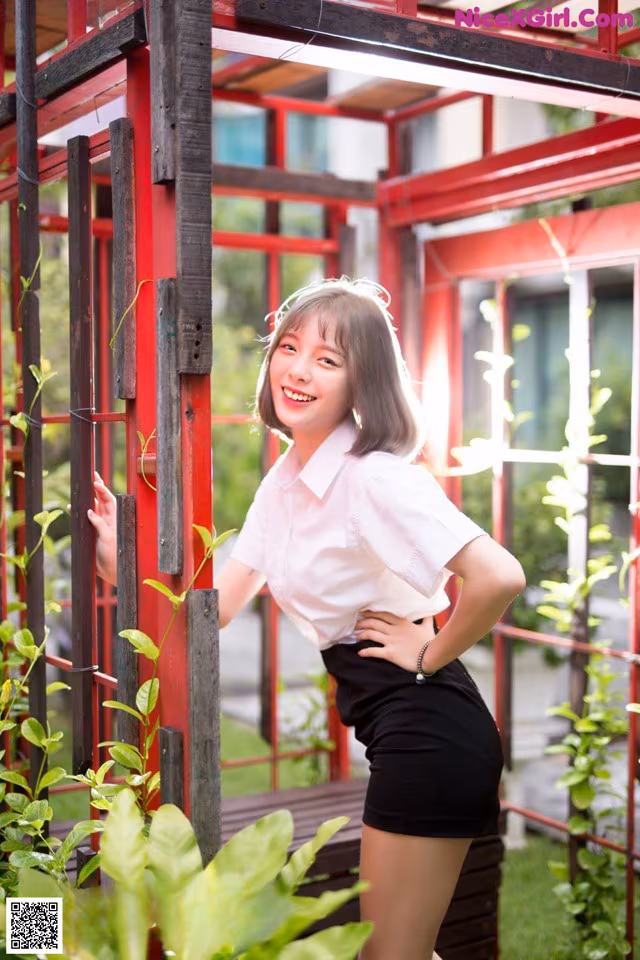 A woman in a white shirt and black skirt posing for a picture.