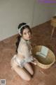 A woman in a white lingerie sitting on the floor next to a basket.