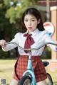 A woman in a school uniform riding a bike.