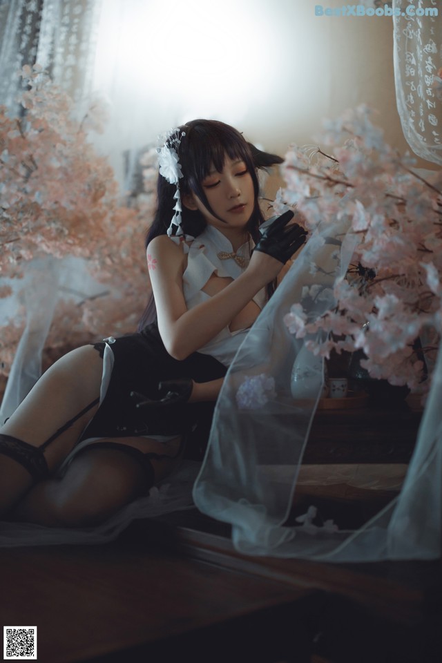 A woman in lingerie sitting on a bed next to a window.