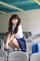 A young woman sitting on a chair in a classroom.