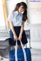 A woman in a school uniform holding a blue bag.