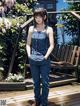 A woman in overalls standing on a wooden deck.