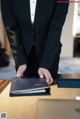 A man in a tuxedo is opening a book on a table.