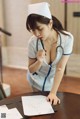 A woman in a nurse uniform writing on a piece of paper.