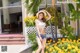 A woman in a white top and denim shorts posing in front of a building.