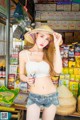 A woman in a straw hat standing in front of a store.