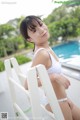 A woman in a white bikini sitting on a white chair.