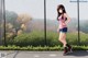 A girl standing in front of a chain link fence.